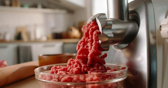 Electric meat grinder mince beef and pork meat in kitchen in daylight. Soft blurred background. Slow zoom out. Advertising. Preparation of minced beef and pork for cutlets, meatballs, chops. Cook food