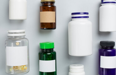 Plastic bottles with vitamins on color background, top view