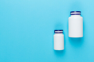 Plastic bottles with vitamins on color background, top view