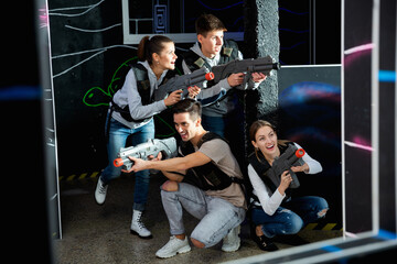 Smiling young friends playing laser tag game with colored laser. High quality photo