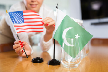 Little flag of Pakistan on table with bottles of water and flag of the USA put next to it by...