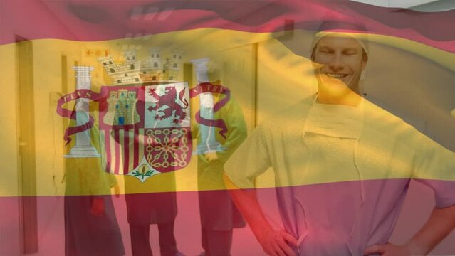 Animation of flag of spain waving over smiling caucasian surgeon standing in corridor of hospital