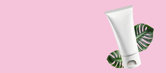 Mock-up of a white tube of cosmetic product on a monstera leaf on a pink background. Banner, Flat...