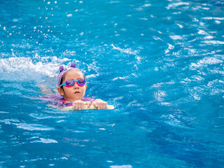 Asian child or kid girl wearing swimming suit to learning on swimming pool , learn and training...