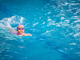 Asian child or kid girl wearing swimming suit to learning on swimming pool , learn and training swim on kick board