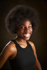 Fototapeta na wymiar Portrait of cheerful young African American woman in black t-shirt with afro hairstyle smiling and looking at the camera