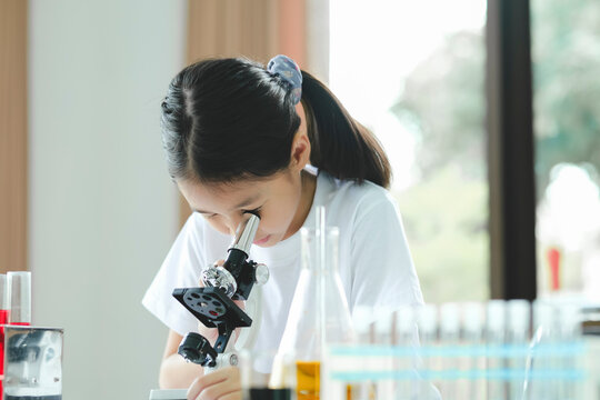 Little child with learning class in school laboratory using microscope