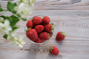 Top view of ripe strawberries in a glass bowl on a wooden table