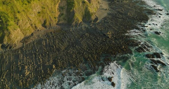 Rough rocky coast land with golden hour glow on hills, New Zealand