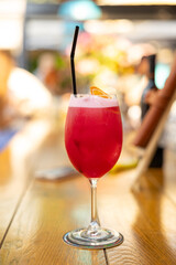 Pink and red Fresh colorful exotic alcoholic cocktail with orange and ice in the bar. Colorful pink Soft drink with ice on the bar desk.