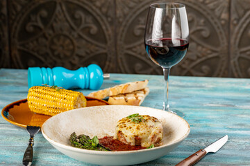 Entrana Argentinean skirt steak under cheese, grilled beef with asparagus, corn and tomato souce on wooden background