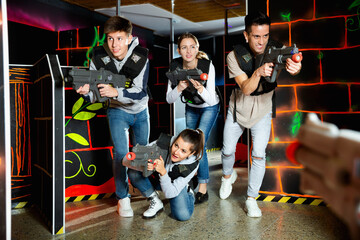 Fototapeta na wymiar Group of young people playing laser tag game with laser guns. High quality photo