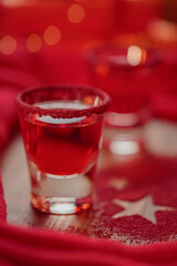 Cranberry vodka shot and Christmas decorations on wooden background. Winter holidays concept.