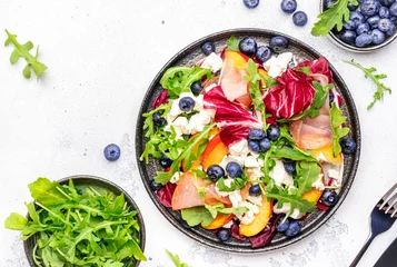  Gourmet fresh salad with arugula, radicchio, sweet peaches, ham, cheese and blueberries. White table background, top view © 5ph