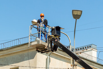 A worker on a lifting platform repairs a street light pole