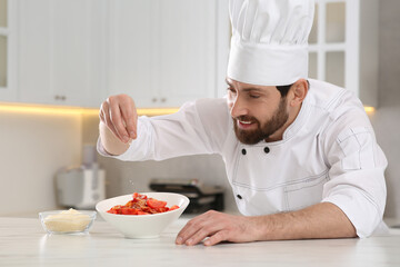 Professional chef adding grated cheese into delicious spaghetti at marble table