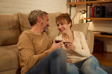 Romantic mature couple relaxing at home and drinking red wine - obrazy, fototapety, plakaty