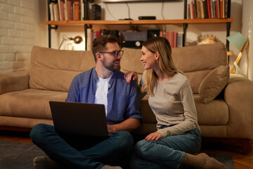 Young couple spending evening at home using laptop