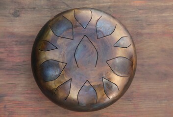 Steel tongue drum on wooden table, top view. Percussion musical instrument