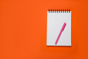 Blank office notebook and pen on orange background, top view. Space for text
