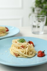 Tasty spaghetti with tomatoes and cheese served on white wooden table, closeup. Exquisite presentation of pasta dish