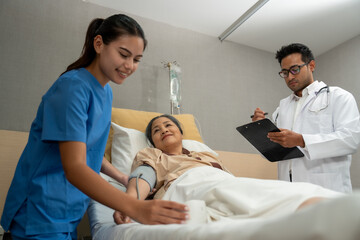 Obraz premium Doctor and nurse measuring blood pressure of patient in recovery room after treatment