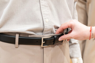 Woman's hand holding a men's trouser belt. Woman Taking Off men's belt.