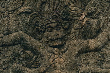 Ancient stone wall carved in sacred monkey forest. Traditional monkey sculpture in ubud sanctuary