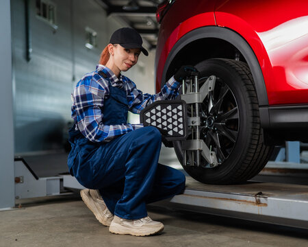 A female auto mechanic makes a camber. Woman working in a car service.