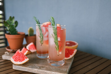 Close-up of drinks on table. Paloma cocktails with grapefruit juice, tequila and rosemary.
