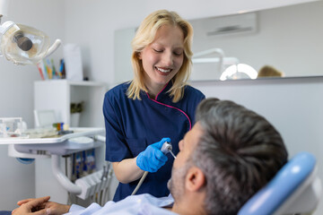 Dentist examining a patient's teeth in the dentist office. Man patient having dental treatment at dentist's office