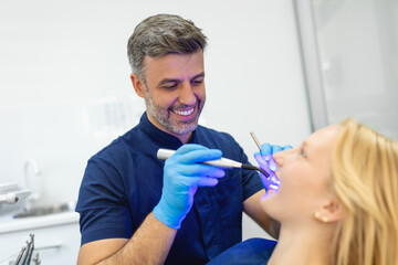 Young woman during dental filling drying procedure with curing UV light at dental clinic.