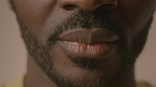 Cropped closeup of lips of bearded Black man speaking at camera
