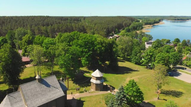 Aerial view Young lithuanians relax on sunday mass by St. Joseph Church in Paluse, Lithuania. Stave Churches in Europe. Old heritage sites. Walls formed by vertical wooden boards.