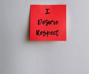 Red note with text written I DESERVE RESPECT stick on grey wall, concept of self remender to demand or earn respect from others never let people treat like a doormat, in workplace or relationship