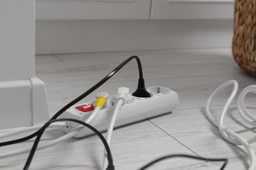 Extension cord with electrical plugs on white floor indoors, closeup