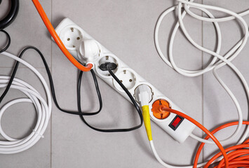 Power strip with electrical plugs on grey floor, flat lay
