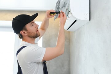 Happy Male Technician Repairing Air Conditioner.