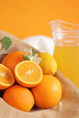 Summer composition with citrus fruits and juice in a carafe. Ripe oranges in a summer hat. Citrus fruits on an orange background. Foods rich in vitamin C. Copy space