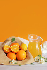 Summer composition with citrus fruits and juice in a carafe. Ripe oranges in a summer hat. Citrus fruits on an orange background. Foods rich in vitamin C