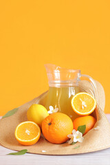 Lemonade from oranges and lemons. Glass jug and citrus fruits in a summer hat. Ripe oranges in a hat. Vitamin drink