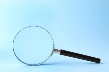 Magnifying glass with handle on light blue background
