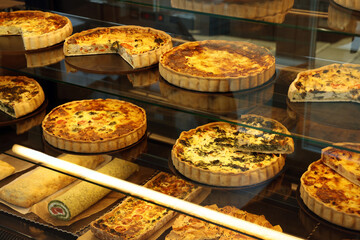 Different delicious quiches on counter in bakery shop