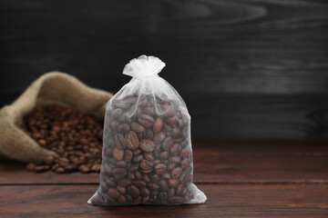 Scented sachet with coffee beans on wooden table, closeup
