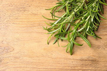 Fresh green rosemary on wooden table, top view. Space for text