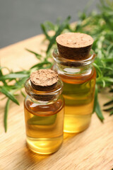 Bottles of essential oil and fresh rosemary sprigs on table, closeup