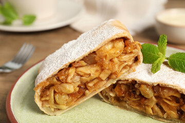 Delicious strudel with apples, nuts and raisins on plate, closeup