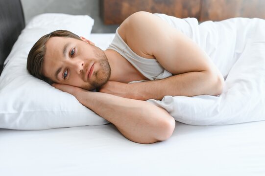 Bright shoot of upset man lies in the bed
