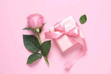 Gift box and beautiful rose flower on pink background, flat lay