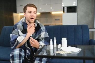 Man wrapped in plaid on the sofa feeling sick illness at home